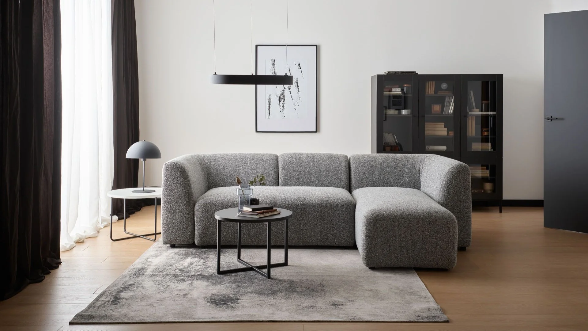 nowoczesny salon z szarą sofą boucle i czarnymi dodatkami
